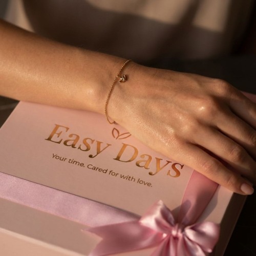 Delikatna złota bransoletka na nadgarstku nastolatki, spoczywająca na pudełku Easy Days.