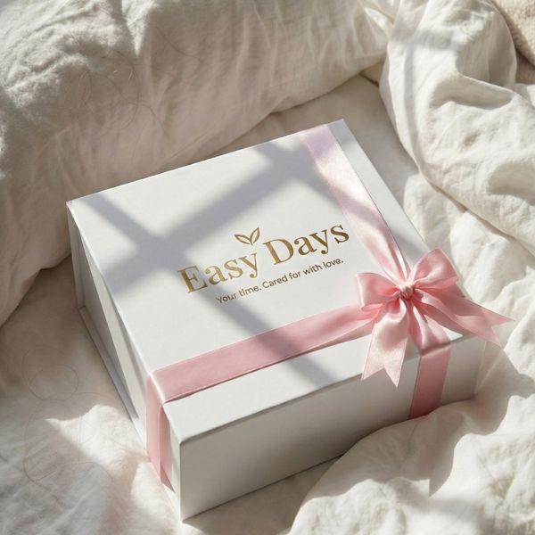 Zamknięty box Easy Days leżący na pościeli w słonecznej sypialni, symbolizujący dyskrecję i komfort.